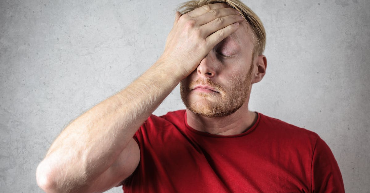 a-man-in-red-shirt-covering-his-face-4689510