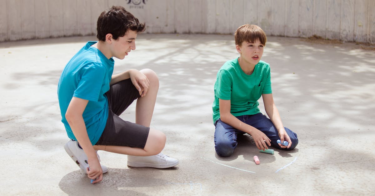 boys-sitting-on-the-concrete-floor-while-holding-chalks-1592843