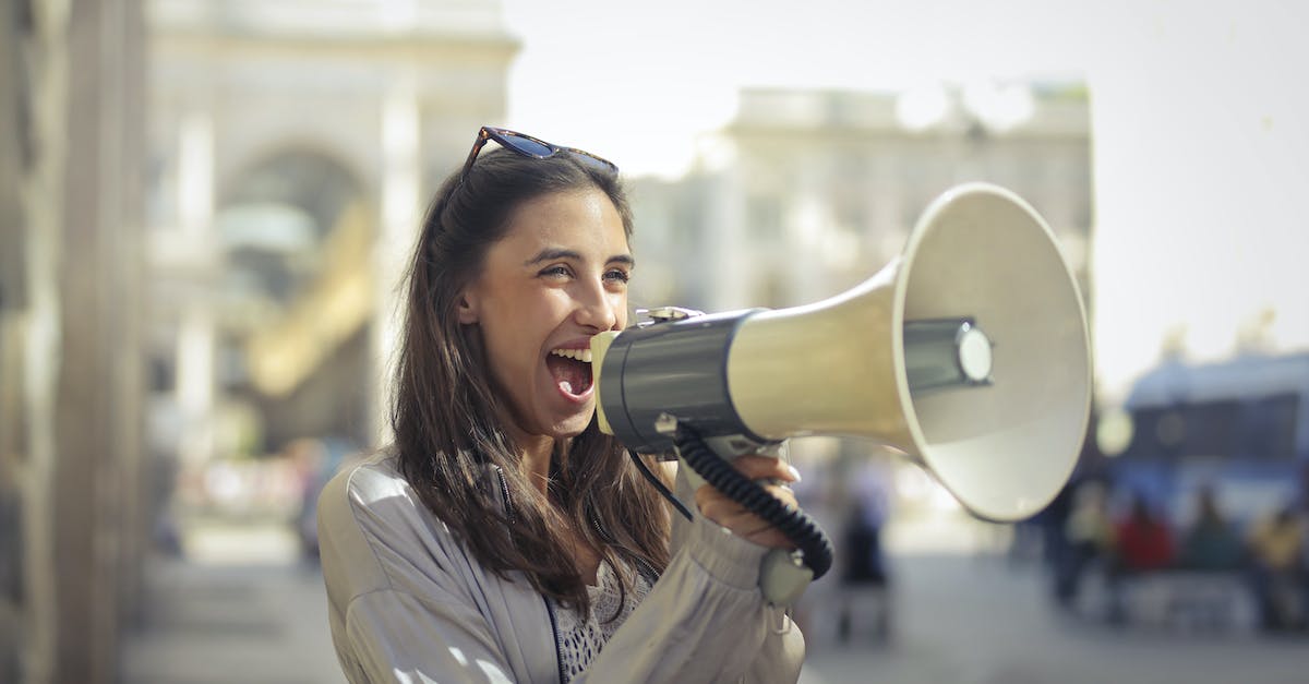 cheerful-young-woman-screaming-into-megaphone-8568244