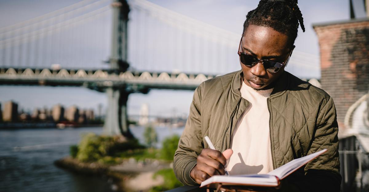 concentrated-young-black-male-checking-schedule-in-notebook-while-standing-on-city-promenade-against-1005508