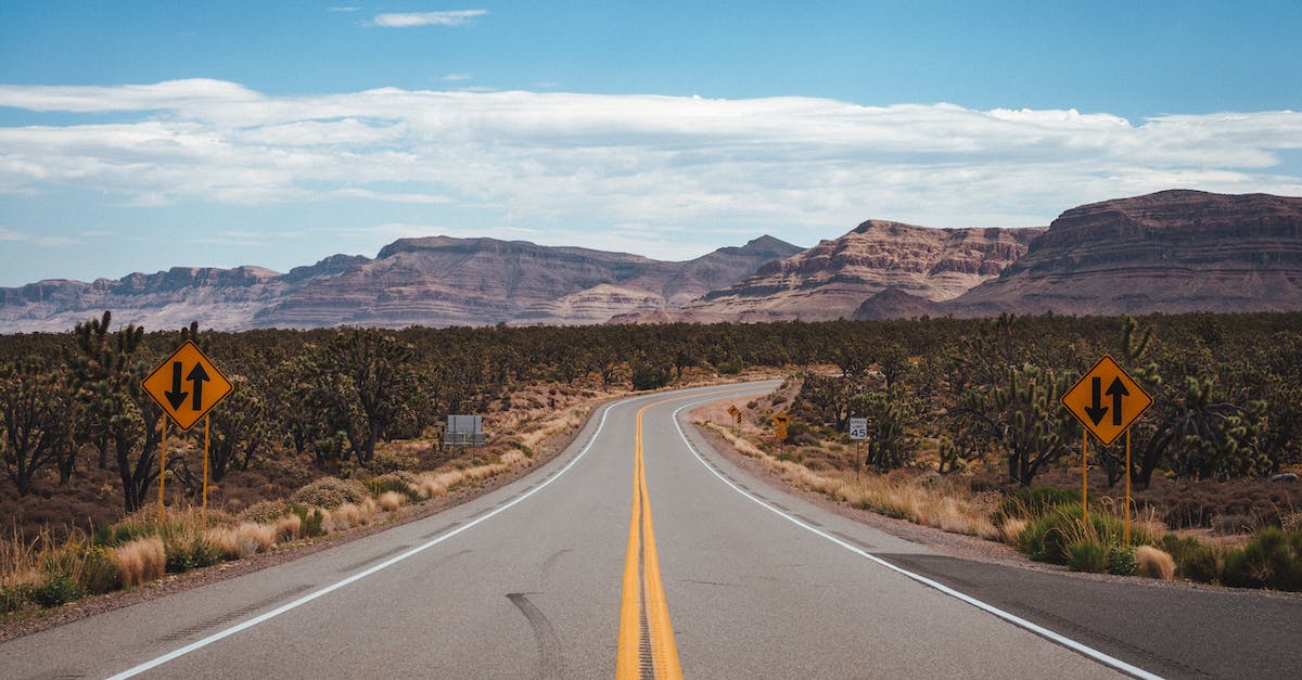 empty-asphalt-road-going-through-cactus-fields-towards-rocky-mountains-against-cloudy-blue-sky-in-un-4163099