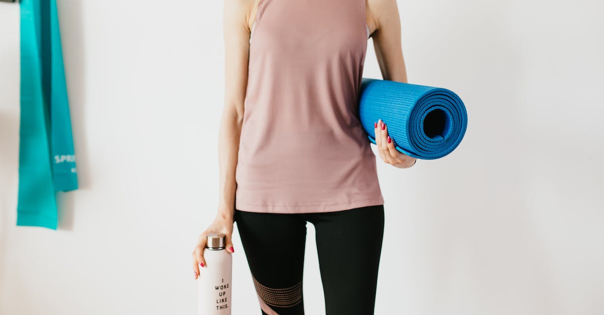 faceless-slim-female-athlete-in-sportswear-standing-with-blue-fitness-mat-and-water-bottle-while-pre-2510446