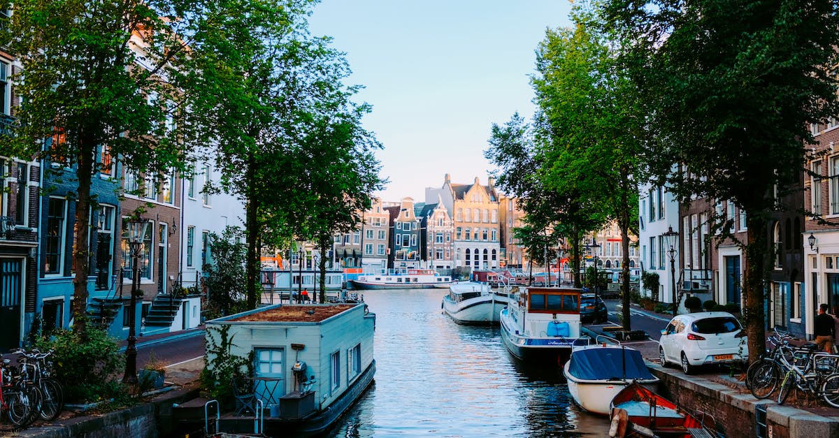 peaceful-scenery-of-amsterdam-streets-with-typical-houses-against-channel-with-moored-boats-on-clear-3344880