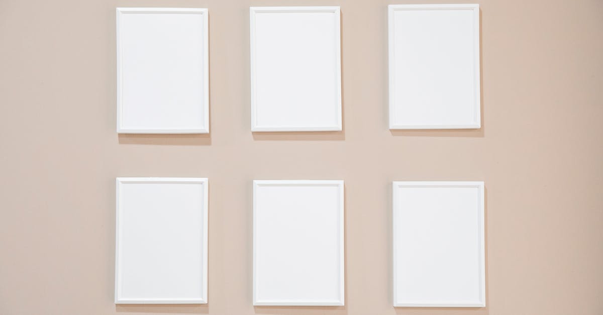 rows-of-blank-white-rectangular-frames-hanging-on-light-pink-wall-in-studio-9151817