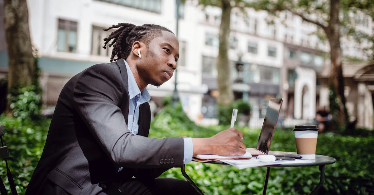 side-view-of-concentrated-young-black-male-writer-listening-to-music-with-true-wireless-earbuds-and-8570412