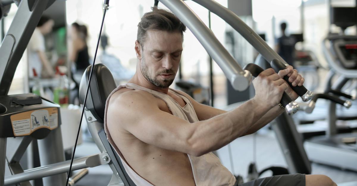 side-view-of-confident-muscular-man-doing-exercises-on-shoulder-press-machine-while-training-in-mode-2093596