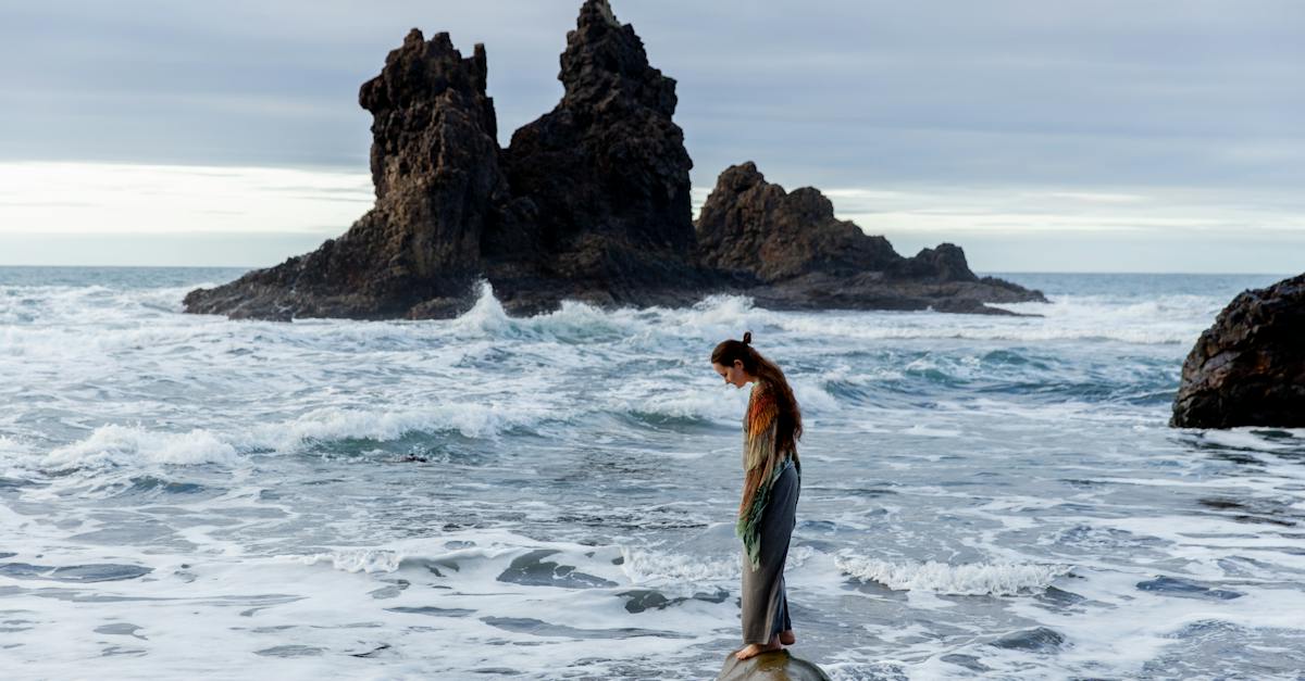 side-view-of-lonely-sad-female-standing-on-stone-in-front-of-storming-ocean-3704042