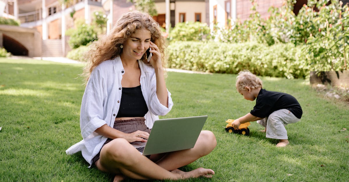 smiling-blonde-woman-sitting-with-laptop-in-garden-9324234