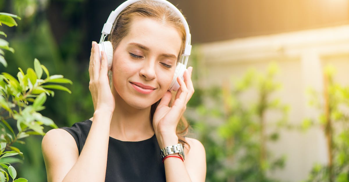 woman-wearing-black-sleeveless-dress-holding-white-headphone-at-daytime-3164825